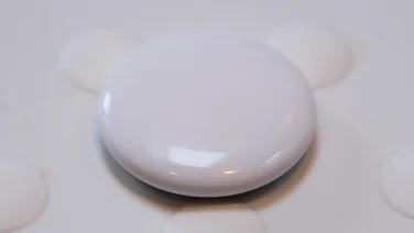 The Apple AirTag (2nd gen) pictured on a white rubber surface