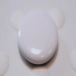The Apple AirTag (2nd gen) pictured on a white rubber surface