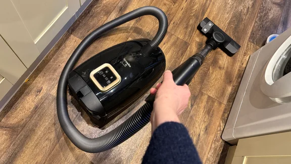 The Miele Guard L1 pictured vacuuming in a kitchen with a dark wood floor