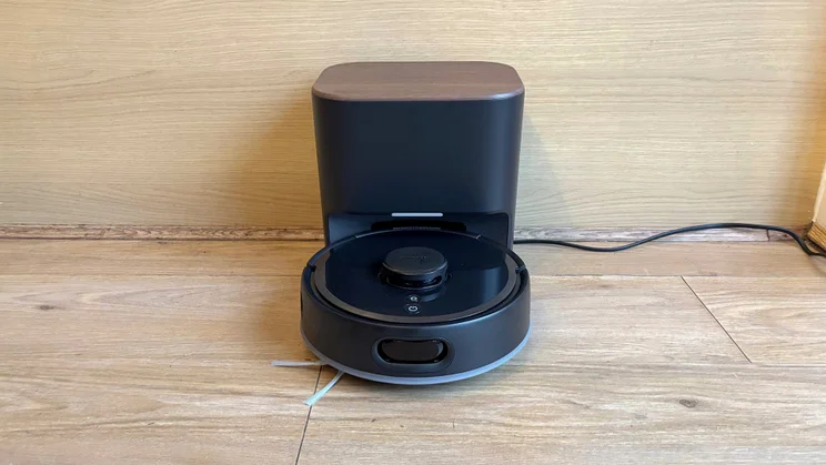 The Switchbot K11+ robot vacuum on its base, on a hard wood floor
