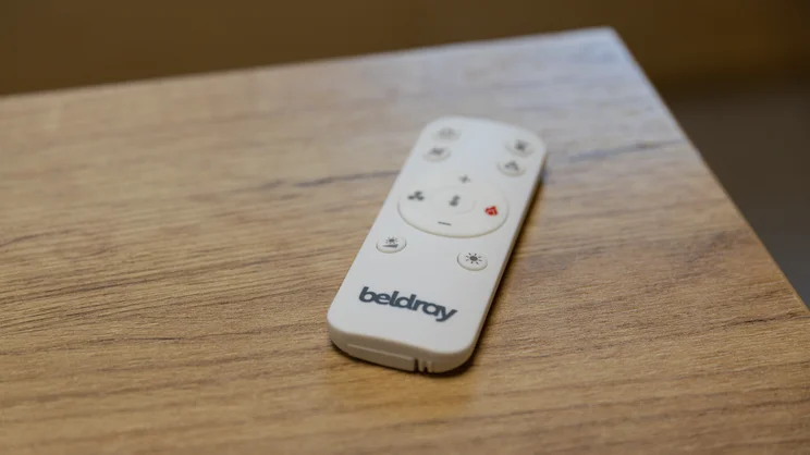 The Beldray 2-in-1 Bladeless Fan's remote control, on the corner of a wooden table