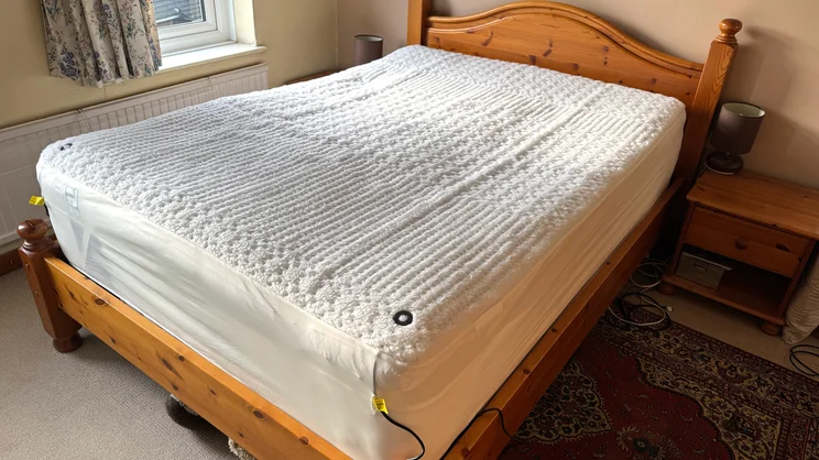 The Beurer Indulgence Heated Underblanket on a bed in a bedroom