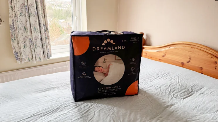 The Dreamland Love Mornings Heated Duvet in its storage bag, on top of a mattress