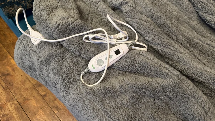 A closeup of the Dunelm Teddy Electric Throw's cable and remote control