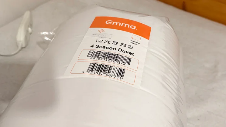 The Emma All Seasons Customisable Duvet vacuum sealed in a plastic bag, on top of a mattress