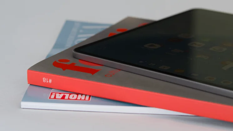 The Honor MagicPad 4 out of its case, on top of a stack of magazines, for context