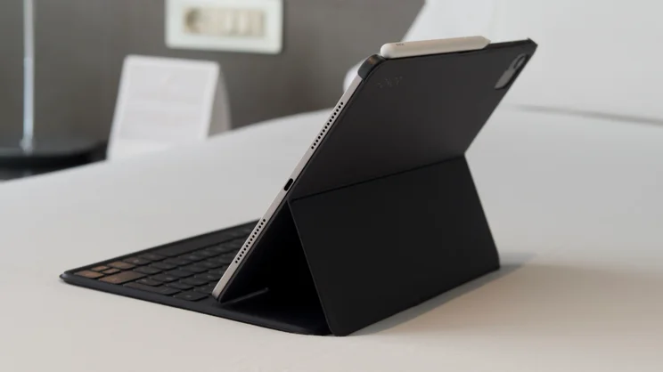 A rear three quarter view of the Honor MagicPad 4 in its keyboard case on on a white bed spread