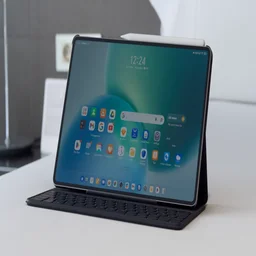 The Honor MagicPad 4 in its keyboard case on on a white bed spread