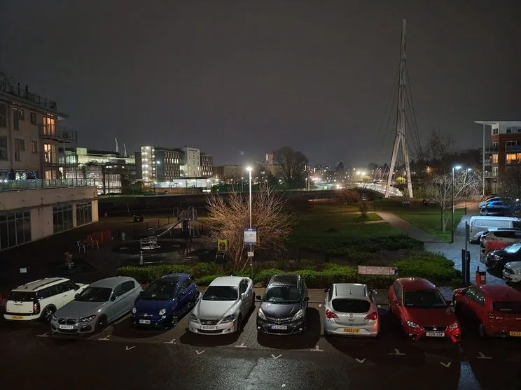 A car park at night with buildings in the distance
