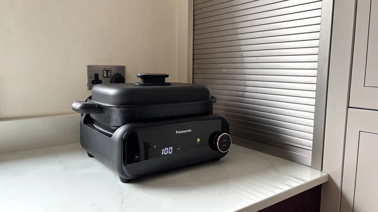 The Panasonic 6-in-1 Table-top Multi Cooker on a kitchen surface. The deep pot is attached, with its lid