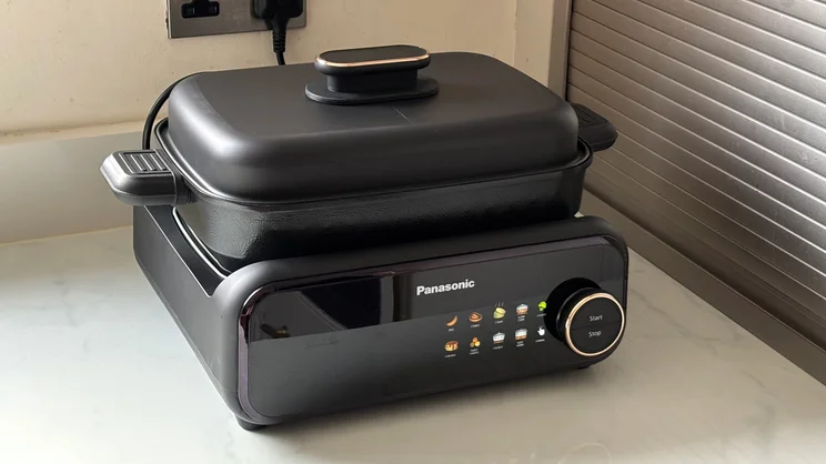 The Panasonic 6-in-1 Table-top Multi Cooker on a kitchen surface. The deep pot is attached, with its lid