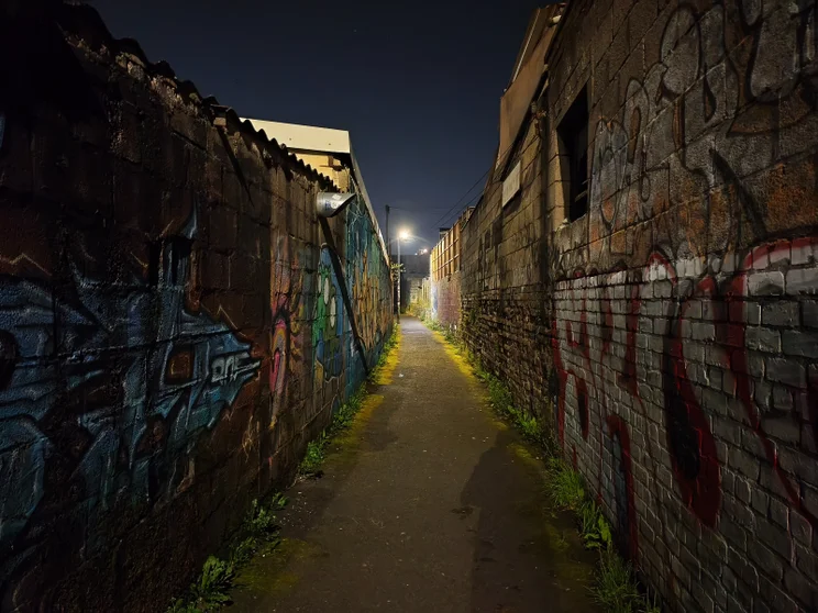 A dark alleyway with graffiti on both walls