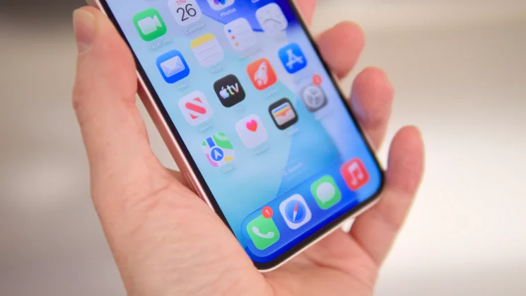 The Apple iPhone 17e in soft pink being held at an angle