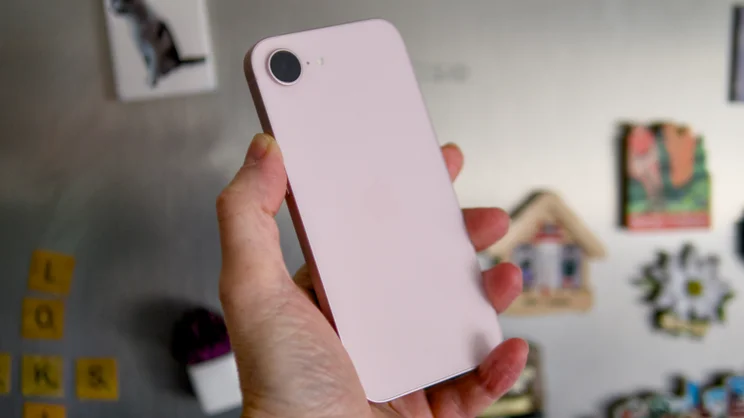 The rear of the soft pink Apple iPhone 17e being held at an angle