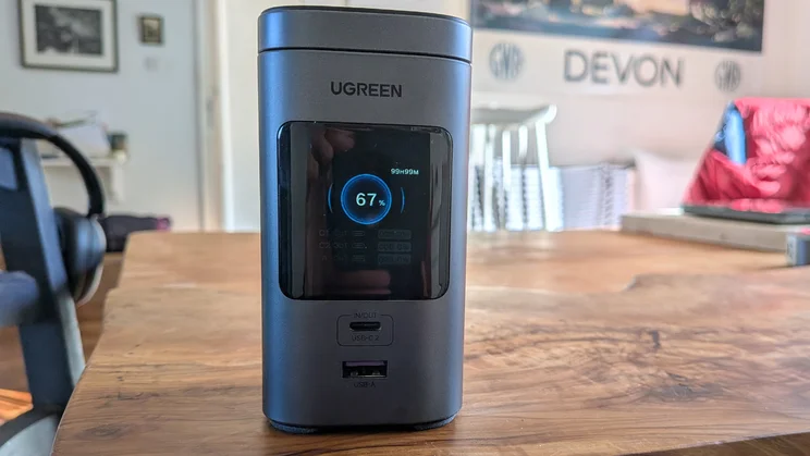 The Ugreen PB771 shown from the front and slightly off to the left side on a wood table with the screen on