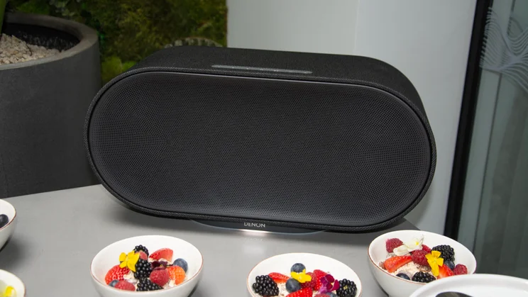 The Denon Home 600 wireless speaker in Charcoal on a table surrounded by bowls of fruit