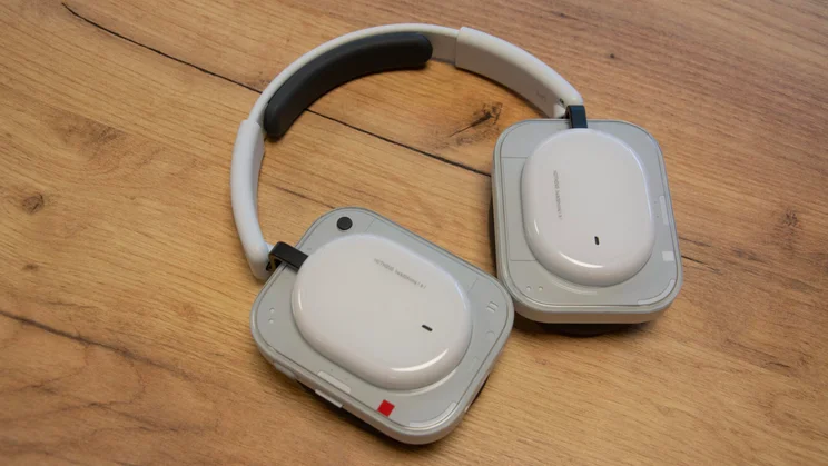 Angled view of the Nothing Headphone (a) over-ear headphones lying face down on a wooden table