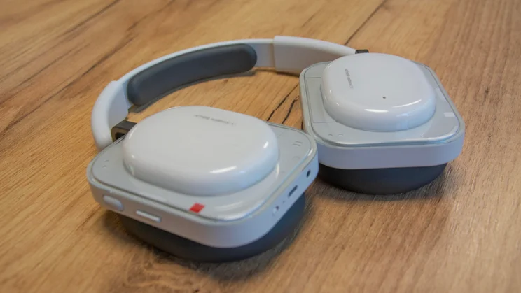 Side view of the Nothing Headphone (a) over-ear headphones face down on a wooden table