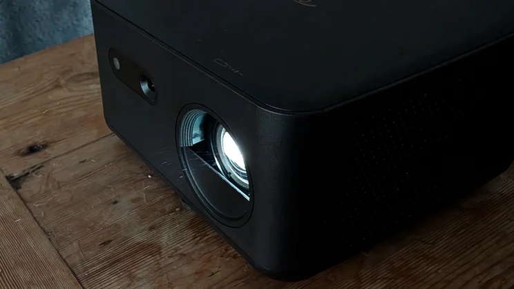 Close-up of the lens of the Optoma Photon Life PK32 projector on a wooden table