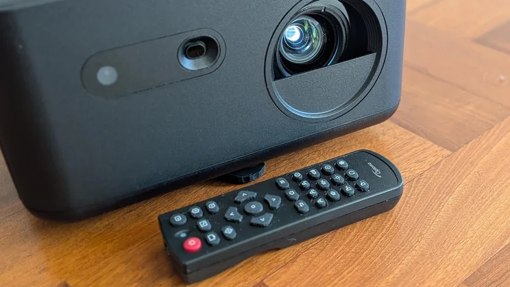 Close-up of the lens of the Optoma Photon Life PK32 projector and its remote control