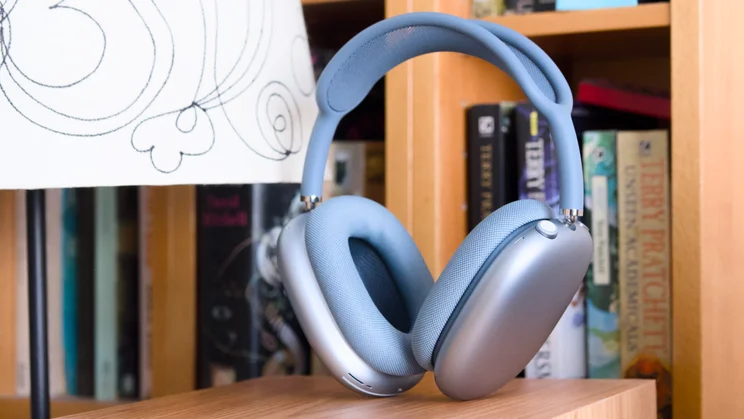 Apple AirPods Max 2 in blue pictured from the front right quarter in front of some bookshelves