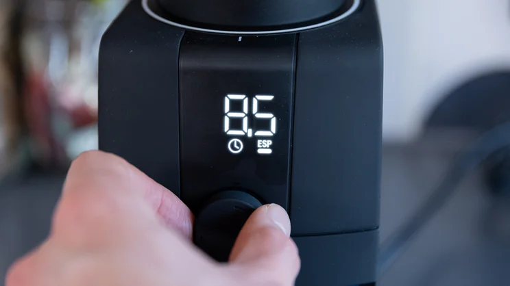 A closeup of the Baratza Encore ESP Pro coffee grinder's digital display, turned on. A hand is turning the dial