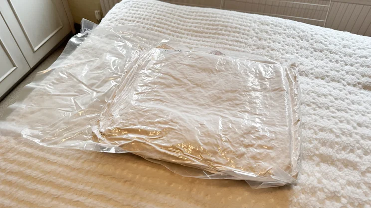 The Dusk Luxury 80% Goose Down duvet vacuum sealed in plastic, on a mattress