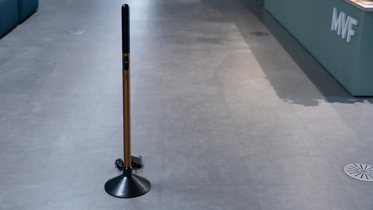 The Dyson PencilWash hard floor cleaner's handle in its charging base, in an office