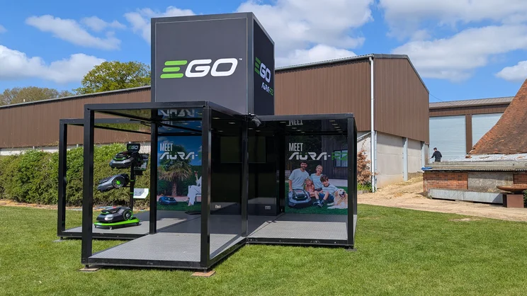 A stand showcasing EGO's Aura R2 robot vacuum's on a farm lawn