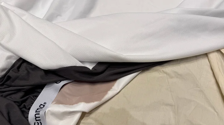 The Emma Mattress Protector lifted away from a bottom sheet to show that no coffee has seeped through