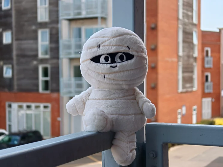 A mummy plushie on a metal railing