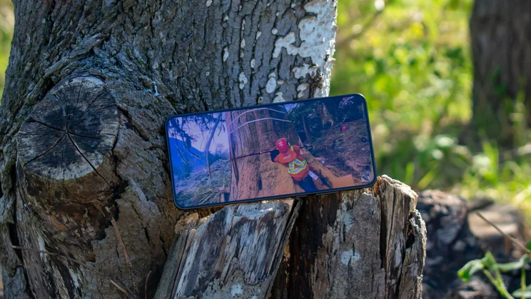 Oppo Find X9 Ultra on a tree stump, displaying a video