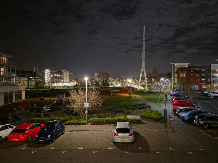 A car park at night, buildings in the distance
