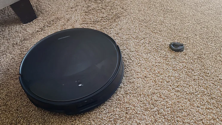 The Saros S20 pictured cleaning a brown carpet, with a fake pet poo in shot