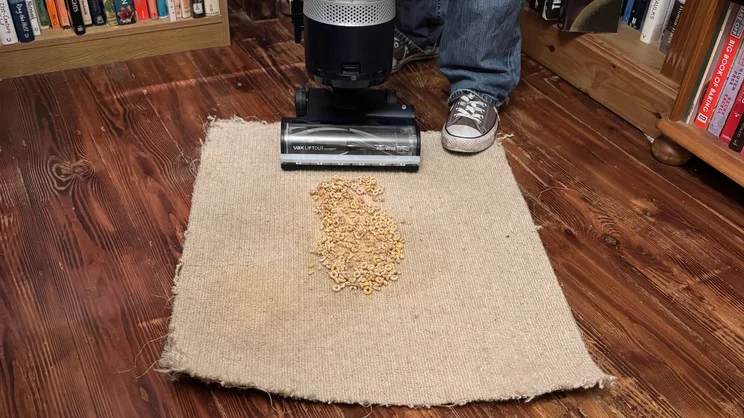 The Vax LiftOut Multi Pet Design Upright Vacuum cleaning cheerios on a piece of beige carpet