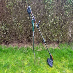 Flymo 18V UltraTrim 300 - wide shot of trimmer propped up on grass