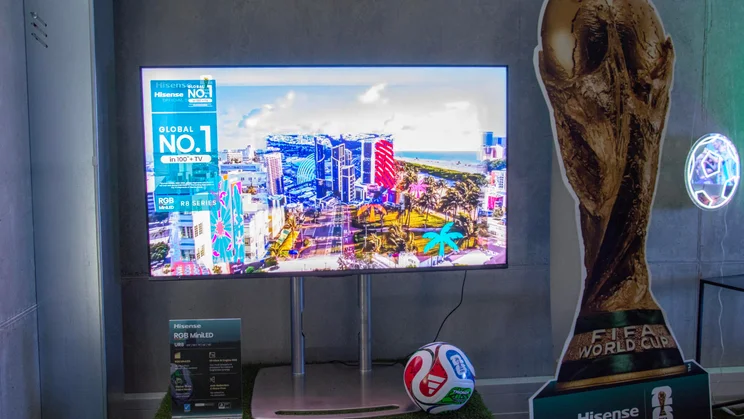 The 55in Hisense UR8S RGB Mini LED TV next to a cardboard cutout of the FIFA World Cup trophy