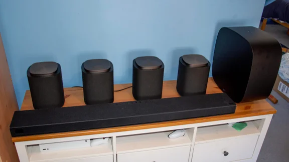 Front view of the LG Sound Suite H7 soundbar, four M7 speakers and the W7 subwoofer on a TV cabinet