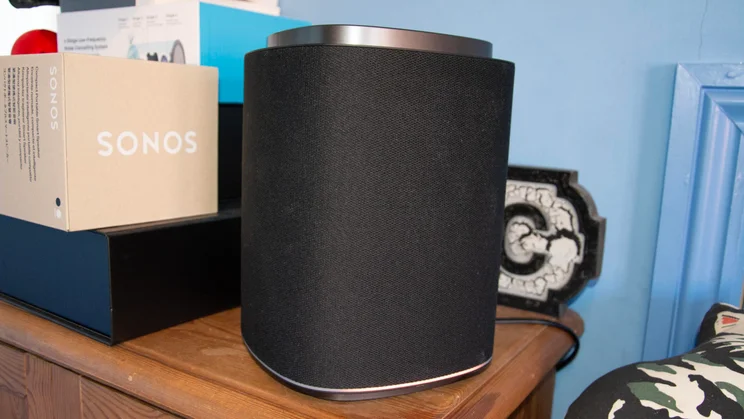 An LG Sound Suite M7 speaker on a wooden cupboard alongside some boxes