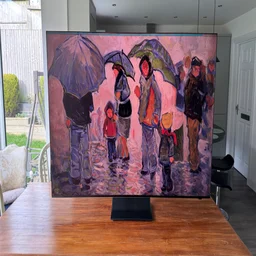 The Samsung R95H Micro LED TV on a wooden table in a conservatory displaying digital artwork of people with umbrellas