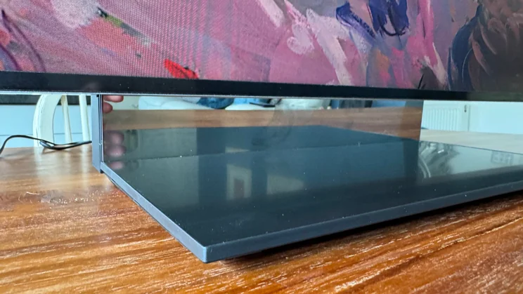 Close-up of the stand of the Samsung R95H Micro LED TV on a wooden table in a conservatory from a low angle