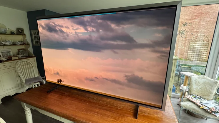Right Front view of the Samsung S99H quantum dot OLED TV displaying a cloudy sky on the savannah