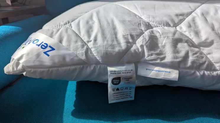 A closeup of the edge of the Cuddledown ZeroMite Hygienic Washable Pillow, with logo and care label