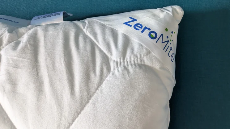 A closeup of the Cuddledown ZeroMite Hygienic Washable Pillow's corner and logo label