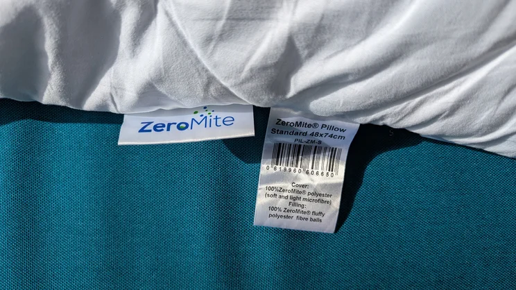 A closeup of the edge of the Cuddledown ZeroMite Hygienic Washable Pillow, with logo and care label