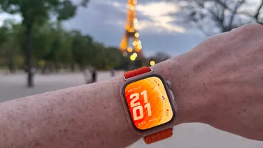 The Huawei Watch Fit 5 Pro on wrist, with the Eiffel Tower lit up in the background