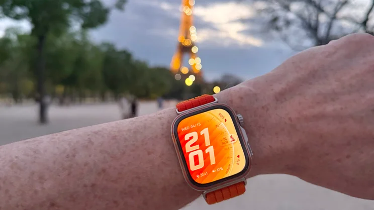 The Huawei Watch Fit 5 Pro on wrist, with the Eiffel Tower lit up in the background