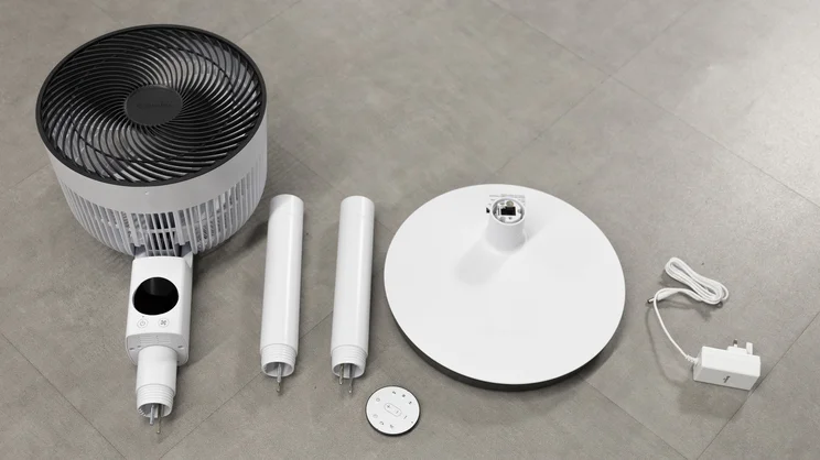 The Meaco Sefte Pro 10in Pedestal Fan in its respective parts, laid out on the floor of an office
