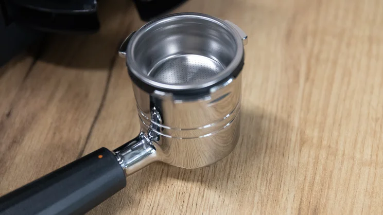 A closeup of the Ninja Luxe Cafe Pro espresso machine's portafilter, on a table in an office