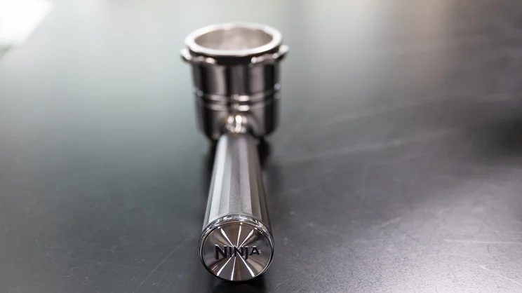 A closeup of the Ninja Luxe Cafe Pro espresso machine's portafilter, on a table in an office